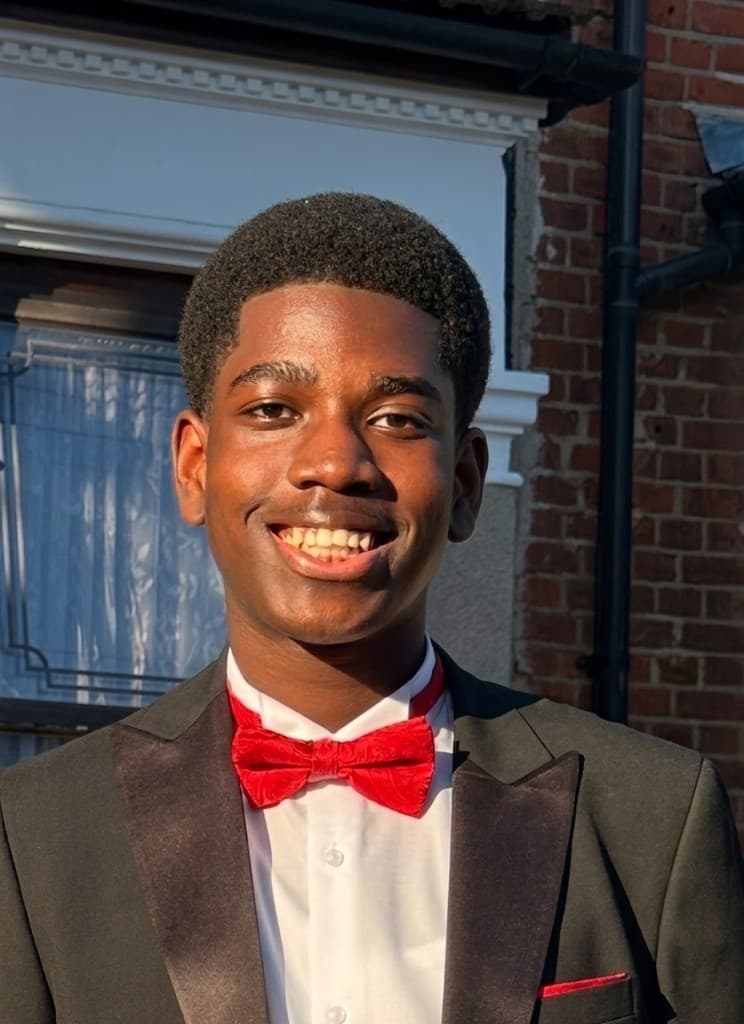 Jermaine, a TTS ambassador, smiling outdoors in formal wear with a red bow tie.