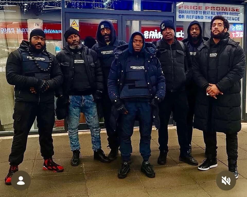 Seven members of the Streetfathers street engagement team standing together in branded jackets on an urban high street